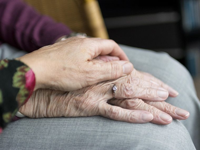 La mano di una persona giovane posata su quella di una persona anziana